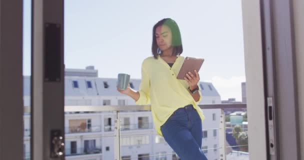 混合种族的性别流体力学者喝一杯咖啡 并在屋顶平台上使用平板电脑 隔离检疫期间单独呆在家里 — 图库视频影像