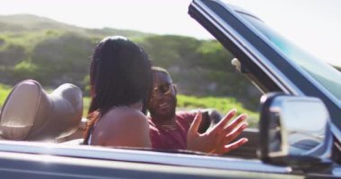 Afro-Amerikalı çift yolda üstü açık arabada otururken eğleniyor. Yolculuk ve macera konsepti