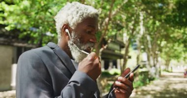 Şirketler parkında akıllı telefondan konuşan Afrikalı Amerikalı son sınıf öğrencisi. aktif kıdemli yaşam tarzı konsepti