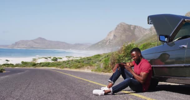非洲裔美国人一边站在被撞坏的汽车旁边一边用智能手机说话 道路旅行和探险概念 — 图库视频影像