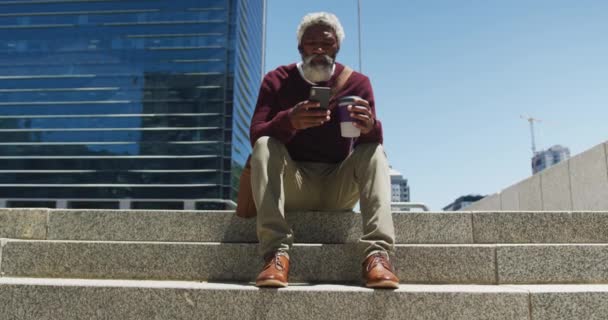 Africano Americano Idoso Segurando Xícara Café Usando Smartphone Enquanto Sentado — Vídeo de Stock