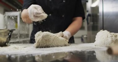 Lastik eldiven takıp hamuru hazırlayan beyaz kadın şefin orta kısmı. Yoğun bir lokanta mutfağında çalışıyorum..