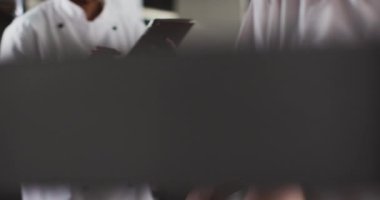Afro-Amerikan kadın aşçı restoran mutfağında tablet kullanıyor. Yoğun bir lokanta mutfağında çalışıyorum..