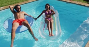 Çeşitli arkadaş grupları yüzme havuzunda şişme kutularla oynarken eğleniyor. Yazın dışarıda takılıp dinleniyorum..