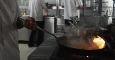 Afrika kökenli Amerikalı erkek aşçının tavada sebze kızartması. Yoğun bir restoran mutfağında çalışıyorum..