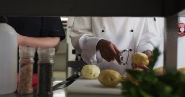 Restoranın mutfağında sebze soyan ve kesen bir grup şefin orta kesimi. Yoğun bir lokanta mutfağında çalışıyorum..