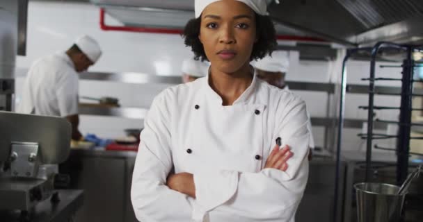 腕を組んでアフリカ系アメリカ人の女性シェフの肖像がカメラを見た 忙しいレストランのキッチンで働く — ストック動画
