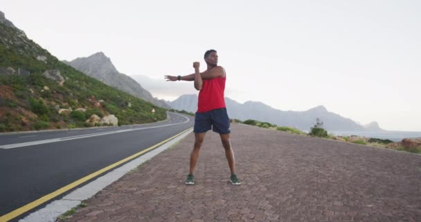 アフリカ系アメリカ人の男が道路に立ちながら腕を伸ばしている フィットネススポーツと健康的なライフスタイルのコンセプト — ストック動画