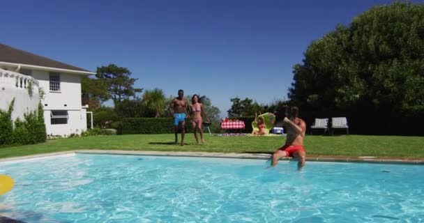 水泳プールに飛び込んできた友人の多様なグループ 夏には屋外でぶら下がったりリラックスしたり — ストック動画