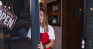 Karışık ırk erkek barista, kapıyı kapatıyor ve tabelayı açık ve kapalı olarak değiştiriyor. Şehirdeki bağımsız küçük işletmeler.