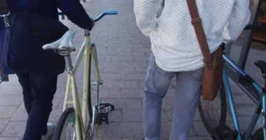 İki farklı erkek arkadaş sokakta bisiklet sürerek birlikte yürüyorlar. Yeşil kentsel yaşam tarzı, şehirde geziyor..