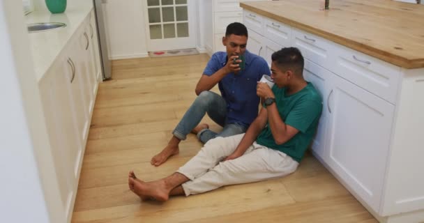 Šťastný Smíšený Závod Gayové Pár Sedí Podlaze Kuchyně Mluví Pije — Stock video