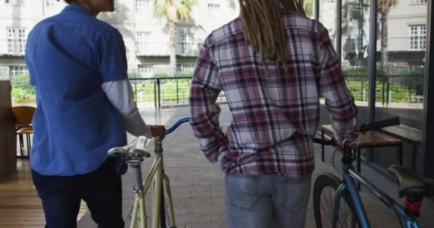Dva různorodé mužské přátele procházející se s koly na ulici. zelený městský životní styl, ven a asi ve městě. .