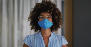 Mavi maske takan kıvırcık saçlı melez bir kadının portresi. Coronavirus covid 19 salgını sırasında dışarı çıkmış..