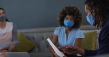 Sıradan bir toplantıda yüz maskesi takan çeşitli iş arkadaşları. Coronavirus covid 19 salgını sırasında iş arkadaşları birlikte çalışıyor..
