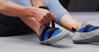 Beyaz bir kadının iç duvarda tırmanma ayakkabısı giymesi. fitness ve boş zaman.