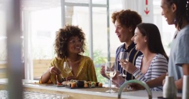 Çeşitli mutlu arkadaşlar şarap içip suşi yiyip barda sohbet ediyorlar. Boş zamanlarımızda sosyalleşiyoruz..