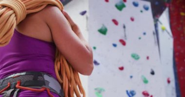 Duvara tırmanırken omzuna halat geçirmiş beyaz bir kadının dikiz manzarası. fitness ve boş zaman.