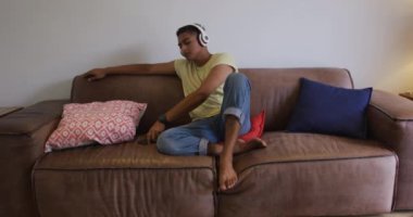 Kulaklık takan, akıllı telefon kullanan ve gülümseyen melez bir yarışçı. Karantina süresince evde tecrit altında kalmak.