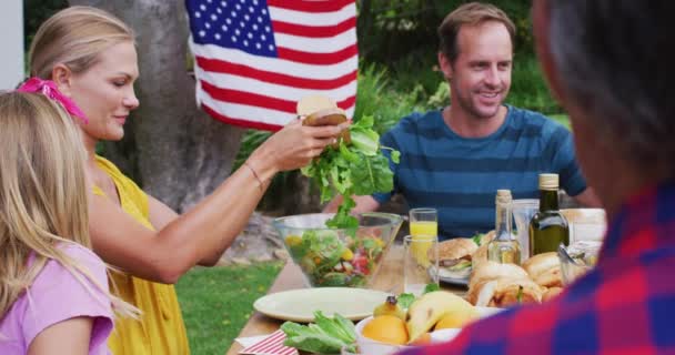 Uśmiechnięta Biała Para Serwująca Rodzinom Wspólny Posiłek Ogrodzie Trzypokoleniowa Rodzina — Wideo stockowe