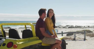 Kumsal arabasında oturup konuşan mutlu beyaz bir çift. Yaz tatili gezisinde plaj durağı.