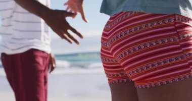 Sahilde el ele tutuşan Afrikalı Amerikalı çiftin orta kesimi. sağlıklı açık hava eğlence zamanı deniz kenarında.