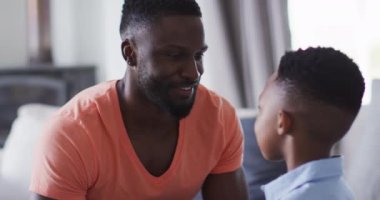 Afrikalı Amerikalı baba ve oğul bir kanepede kucaklaşıyorlar. Karantina süresince evde tek başına kalmak..