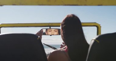 Deniz kenarında plaj arabasında oturup makyaj yapan mutlu beyaz kadın. Yaz tatili gezisinde plaj durağı.