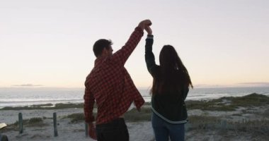 Kumsalda deniz kenarında dans eden mutlu beyaz çift. Yaz tatili gezisinde plaj durağı.