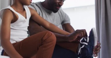 Afrikalı Amerikalı baba, oğluna yatak odasında giyinmesinde yardım ediyor. Karantina süresince evde tek başına kalmak..