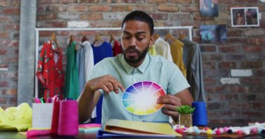 Melez erkek moda tasarımcısı palet renkleri gösteriyor kameraya bakıyor ve gülümsüyor. bağımsız yaratıcı tasarım işi.