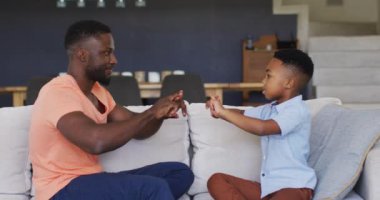 Afrikalı Amerikalı baba oğluna işaret dilini öğretiyor. Karantina süresince evde tek başına kalmak..