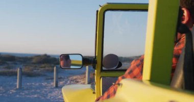 Deniz kenarındaki plaj arabasında oturan mutlu beyaz adam. Yaz tatili gezisinde plaj durağı.