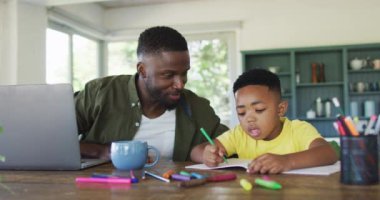 Afrika kökenli Amerikalı baba ve oğul ödev yapıyor ve birlikte dizüstü bilgisayar kullanıyorlar. Karantina süresince evde tek başına kalmak..