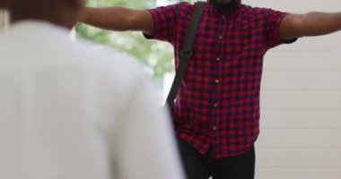 Afro-Amerikan oğlu koşuyor ve gülümseyen babasına sarılıyor. Mutlu aile evde birlikte vakit geçiriyor..