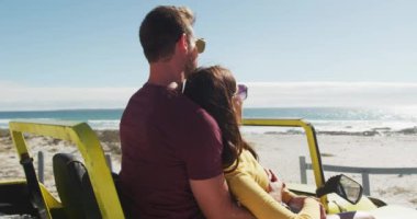 Kumsal arabasında oturup konuşan mutlu beyaz bir çift. Yaz tatili gezisinde plaj durağı.