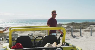 Kumsal arabasında oturup konuşan mutlu beyaz bir çift. Yaz tatili gezisinde plaj durağı.