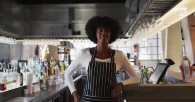 Kameraya bakıp gülümseyen Afro-Amerikan bayan kafe çalışanının portresi. küçük bağımsız iş.