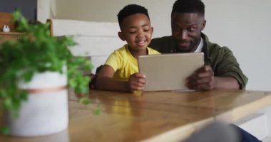 Afrikalı Amerikalı baba ve oğlu dijital tablet kullanıyorlar. Karantina süresince evde tek başına kalmak..