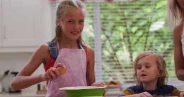 Mutfakta kız ve oğluyla birlikte, önlük giymiş, yumurta kıran bir kız. Karantina süresince evde tecrit altında kalmak.