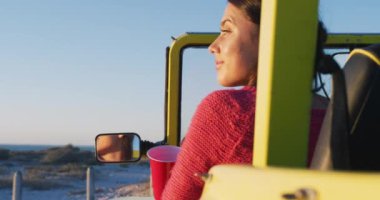 Deniz kenarında plaj arabasında oturup içki içen mutlu beyaz kadın. Yaz tatili gezisinde plaj durağı.