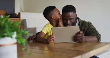 Afrikalı Amerikalı baba ve oğlu dijital tablet kullanıyorlar. Karantina süresince evde tek başına kalmak..