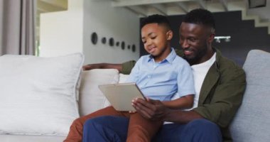 Afrikalı Amerikalı baba ve oğlu dijital tablet kullanıyorlar. Karantina süresince evde tek başına kalmak..