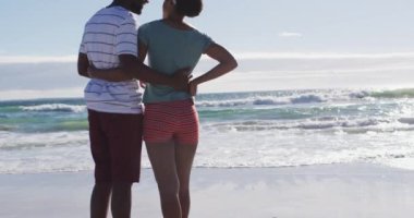 Afrika kökenli Amerikalı çift kumsalda gülümsüyor ve kucaklaşıyorlar. sağlıklı açık hava eğlence zamanı deniz kenarında.