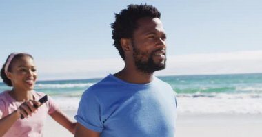 Afrika kökenli Amerikalı bir çift akıllı telefonuyla selfie çekiyor. Sahilde kadını sırtında taşıyan bir adam. sağlıklı açık hava eğlence zamanı deniz kenarında.