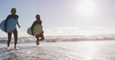 Sahilde sörf tahtası olan Afrikalı Amerikalı bir çift. Tatil ve deniz kenarında sağlıklı vakit geçirme zamanı..