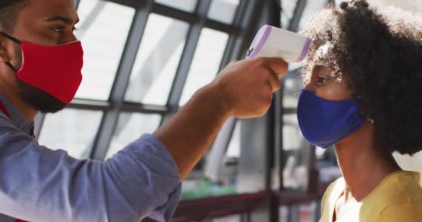 混血咖啡店的男工戴着面罩 测量女同事的体温 食管癌大流行期间的独立小企业D — 图库视频影像