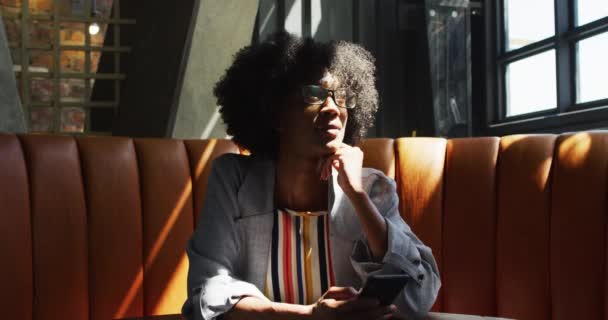 Mujer Afroamericana Sentada Cafetería Mirando Ventana Sonriendo Nómadas Digitales Movimiento — Vídeos de Stock