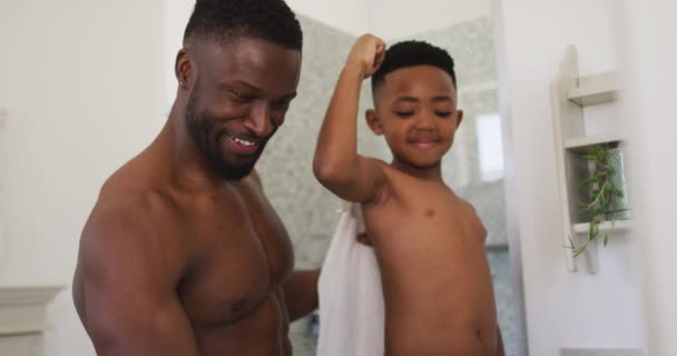 アフリカ系アメリカ人の父親と息子が鏡の中で体を曲げながら一緒に自撮り 隔離されたまま家にいると — ストック動画