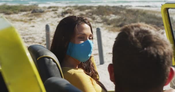 ハッピー白人のカップルの顔のマスクのビーチバギーに座って着ている コロナウイルス コヴィド19パンデミックの夏休みのロードトリップでビーチは立ち止まり — ストック動画